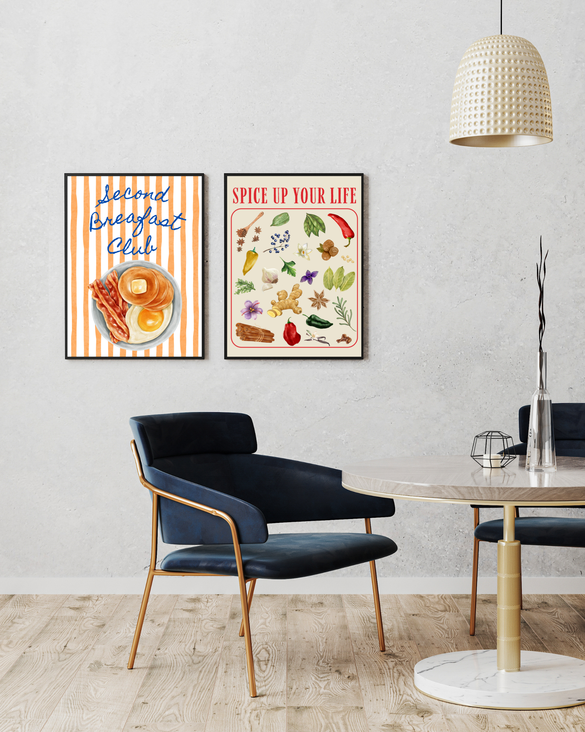 “Two framed wall art prints on a light grey wall above a modern dining set: one with orange stripes, pancakes and ‘Second Breakfast Club’ text; the other with herbs, spices and ‘Spice Up Your Life’ title. Contemporary decor with navy chairs and gold accents.”