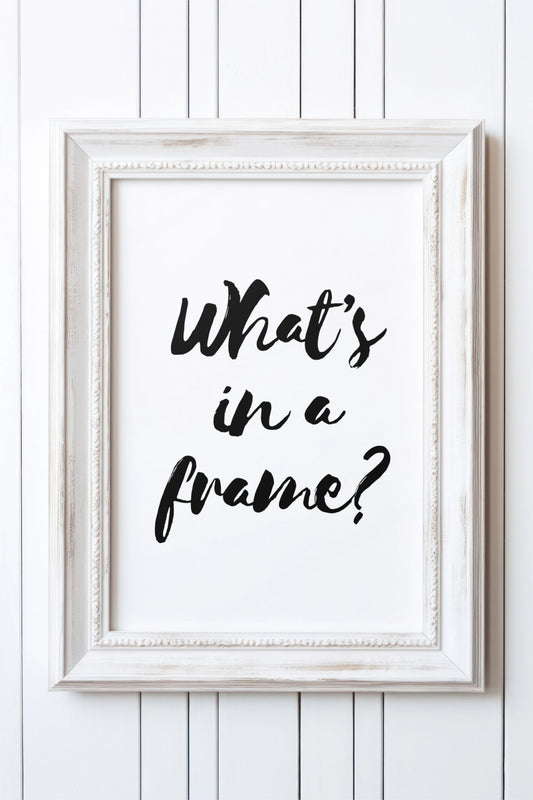 Distressed white wooden frame on a white panelled wall, displaying a black brush-script print that reads "What's in a frame?