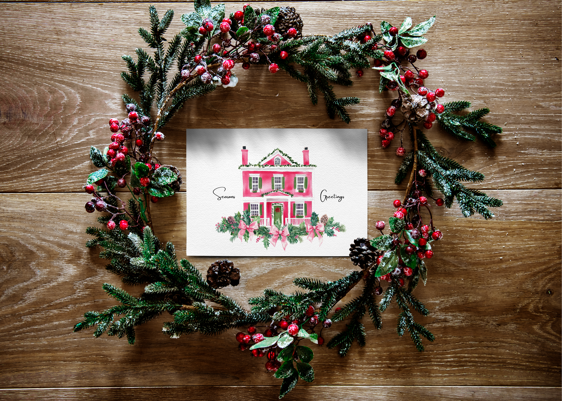 Decorative Christmas wreath with a  christ mas card festive house illustration on a wooden surface