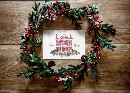Decorative Christmas wreath with a  christ mas card festive house illustration on a wooden surface